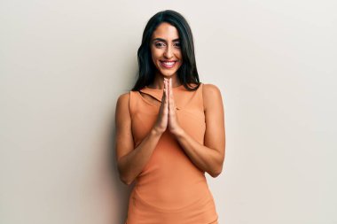 Güzel İspanyol kadın yaz elbisesi giyip ellerinin birarada dua ederek af diliyor kendinden emin bir şekilde gülümsüyor. 