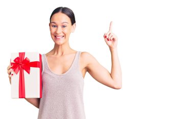 Elinde hediyesini tutan güzel esmer bir kadın bir fikre ya da soru işaretine şaşırmış ve mutlu bir yüzle bir numarayı işaret ediyor. 