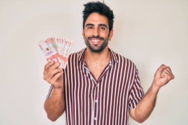 Kolombiya pezosu sakallı yakışıklı adam gururla bağırıyor, zaferi ve başarıyı kutluyor. 