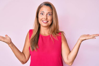 Orta yaşlı İspanyol kadın gündelik giysiler giyiyor ve kolları açık, hiçbir fikrim yok ve şüpheli bir yüz var.. 