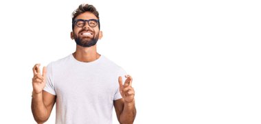 Gündelik kıyafetler giyen ve gözlüklü genç İspanyol adam umut ve gözlerin kapalı gülümseyerek el sallıyor. Şans ve batıl inançlar. 