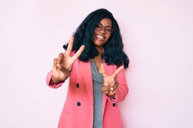 İş ceketi ve gözlük takan güzel Afrikalı kadın kameraya bakıp zafer işareti yapıyor. İki numara.. 