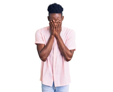 Genç, Afro-Amerikan bir adam, günlük kıyafetler giyiyor ve ağlarken suratını ellerle kapatıyor. depresyon kavramı. 