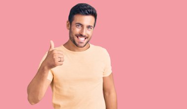 Gündelik kıyafetler giyen genç İspanyol adam elleriyle mutlu bir jest yapıyor. Kameraya bakıp başarıyı gösteren ifade. 