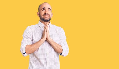 Zarif bir gömlek giyen yakışıklı bir adam elleri bağlı yalvarıyor ve dua ediyor. Yüzünde umut ifadesi var. Çok duygusal ve endişeli. Yalvarıyor. 