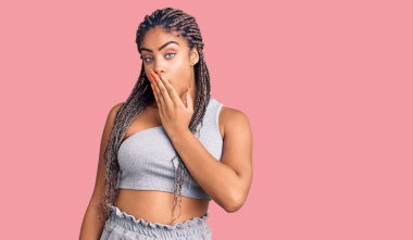 Saçları örülü genç Afro-Amerikalı kadın spor kıyafetleri giymekten sıkılmış, ağzını eliyle kapatmaktan sıkılmış. Huzursuz ve uykulu.. 