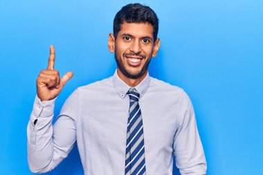 İş elbiseleri giyen genç latin adam başarılı bir fikri işaret ediyor. Heyecanlı ve mutlu. Bir numara.. 
