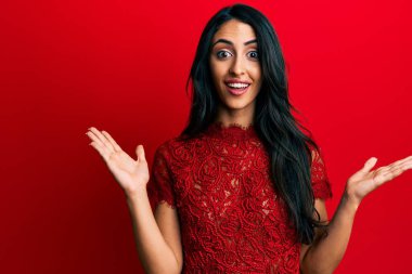 Kırmızı arka planda zarif kıyafetler giyen güzel İspanyol kadın zaferi mutlu bir gülümsemeyle ve ellerini kaldırarak kazanan ifadeyle kutluyor. 