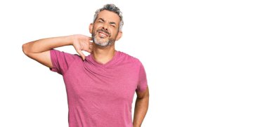 Orta yaşlı, gri saçlı, sıradan kıyafetler giyen boyun ağrısı çeken, elle boyuna dokunan, kas ağrısı çeken bir adam. 