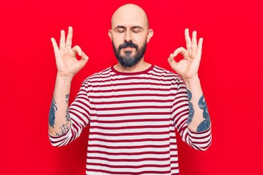 Gündelik kıyafetler giyen genç yakışıklı adam rahatla ve gözleri kapalı gülümse parmaklarıyla meditasyon hareketi yapıyor. yoga konsepti. 