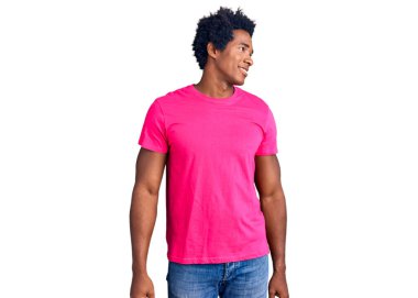 Afro saçlı, sıradan pembe tişörtlü, yüzünde gülümseme, doğal bir ifade olan yakışıklı Afro-Amerikalı bir adam. Kendinden emin gülen. 