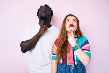 Irklar arası çiftler günlük kıyafetler giyip kuşkuya yoğunlaşmışlar. Parmakları çenelerinde ve yukarı bakıp merak ediyorlar. 