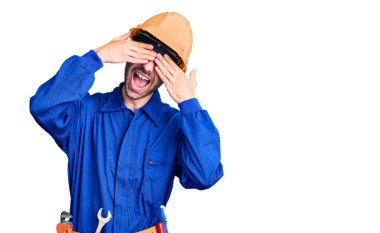 Genç İspanyol adam işçi üniforması giyiyordu. Gözleri kapatıyordu. Neşeli ve komik gülümsüyordu. kör kavram. 