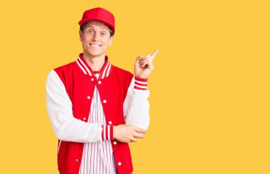 Beyzbol forması giyen yakışıklı genç adam gülümsüyor. 