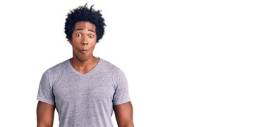 Afro saçlı, sıradan kıyafetler giyen, dudaklı balık suratlı, çılgın ve komik jestler yapan yakışıklı Afro-Amerikan bir adam. Komik ifade. 