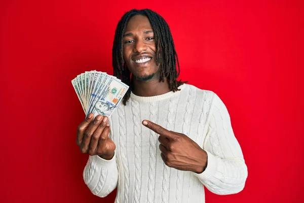 Afrikansk Amerikansk Man Med Flätor Håller Dollar Ler Glad Pekar — Stockfoto