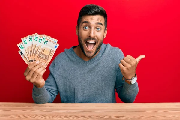 Hombre Hispano Guapo Sosteniendo Montón Billetes Euros Apuntando Con Pulgar —  Fotos de Stock