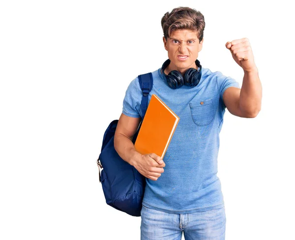 Joven Hombre Guapo Con Mochila Estudiante Auriculares Sosteniendo Libro Molesto —  Fotos de Stock