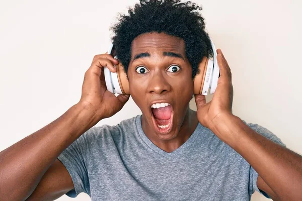 Yakışıklı Afro saçlı, müzik dinleyen kulaklık takan çılgın ve başarıyı kutlayan, gözleri açık, heyecanla haykıran afro-amerikalı adam.. 