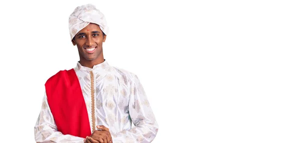 伝統的なシャーワニを身に着けているアフリカのハンサムな男は手で一緒に服を見て リラックスして陽気な笑顔指を越えました 成功と楽観は — ストック写真