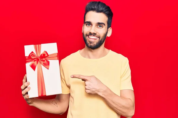 Jovem Homem Bonito Com Barba Segurando Presente Sorrindo Feliz Apontando — Fotografia de Stock