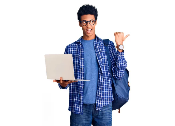 Joven Afroamericano Hombre Sosteniendo Mochila Estudiante Usando Portátil Apuntando Pulgar —  Fotos de Stock