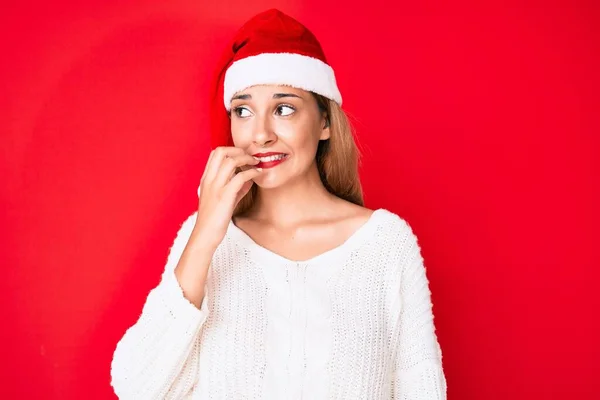 年轻的黑发女人戴着圣诞帽 看上去很紧张 双手放在咬指甲的嘴上 焦虑问题 — 图库照片