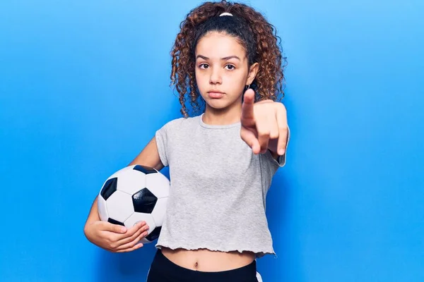 漂亮的小女孩 拿着足球 用手指着相机 对着你 自信地摆出一副严肃的姿势 — 图库照片