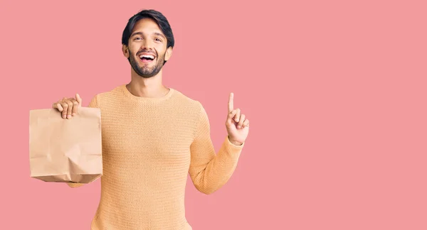 Bonito Homem Hispânico Segurando Tirar Saco Papel Surpreso Com Uma — Fotografia de Stock