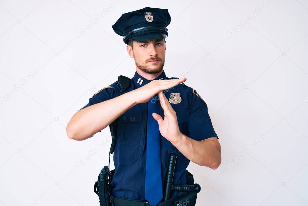 Young caucasian man wearing police uniform doing time out gesture with hands, frustrated and serious face 