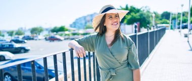 Genç İspanyol kadın tatilde mutlu bir şekilde gülümsüyor. Kentin caddesinde korkuluğa yaslanıyor.