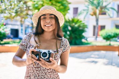 Şehrin caddesinde gezen eski model kamera kullanan genç Latin kadın..
