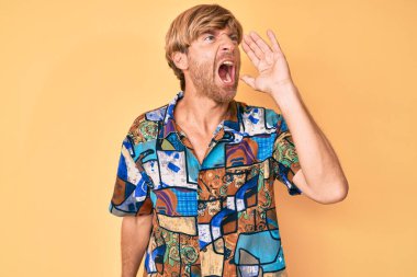 Yazlık tişört giyen genç sarışın adam bağırıyor ve ağızdan ağıza bağırıyor. iletişim konsepti. 