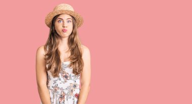 Yazlık şapka takan, komik yüzlü güzel beyaz kadın. Havayla şişmiş ağız, çılgın bir ifade.. 