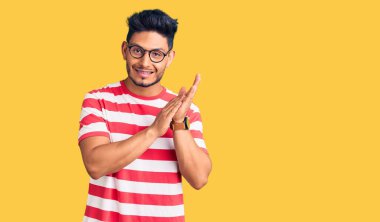 Yakışıklı Latin Amerikalı genç adam gündelik kıyafetler ve gözlük takıyor alkışlıyor ve mutlu ve neşeli, gururlu elleri alkışlıyor. 