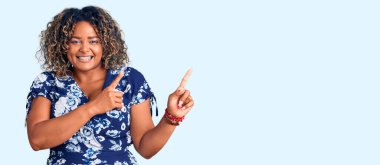 Genç Afro-Amerikan artı cüsseli kadın. Günlük kıyafetler giyiyor. Gülümsüyor ve kameraya bakıyor.. 