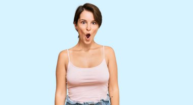 Kısa saçlı, yaz kıyafetleri giyen, ağzı açık, korkmuş ve şaşırmış esmer bir kadın. 