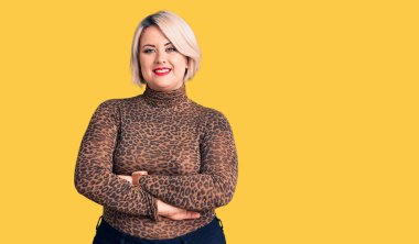 Sıradan bir leopar tişörtü giyen, kollarını kavuşturup kameraya gülümseyen sarışın ve cüsseli bir kadın. pozitif kişi. 