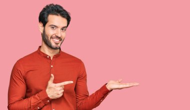 Gündelik kıyafetler giyen genç İspanyol adam kameraya hayret ediyor ve gülümsüyor.. 