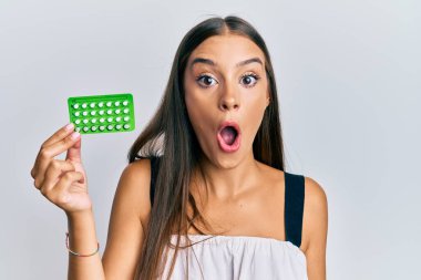 Elinde doğum kontrol hapları tutan Latin kökenli genç bir kadın ağzı açık kalmış, korkmuş ve hayrete düşmüştü. 