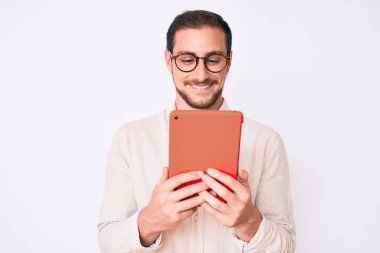 Genç yakışıklı adam dokunmatik bir cihaz kullanıyor. Pozitif ve mutlu görünüyor. Duruyor ve gülümsüyor. 