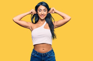 Güzel İspanyol kadın günlük kıyafetler giyip gülümsüyor kulaklarını parmaklarıyla çekiyor, komik bir jest. deneme sorunu 