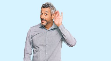 Orta yaşlı, gri saçlı, günlük kıyafetler giyen, ağzı kulaklarında gülümseyen, dedikoduları ve dedikoduları dinleyen bir adam. Sağırlık kavramı. 