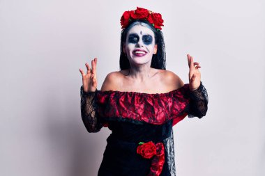 Ölü makyajlı Meksika günü takan genç bir kadın umut ve gözlerin kapalı bir şekilde gülümseyerek bana işaret etti. Şans ve batıl inançlar. 