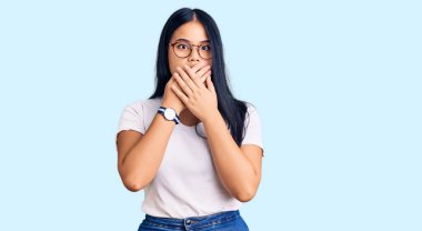 Gündelik kıyafet ve gözlük takan genç güzel Asyalı kız yanlışlıkla elleriyle ağzını kapatırken şok oldu. gizli kavram. 