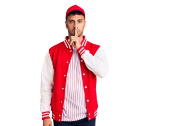 Beyzbol forması giyen genç İspanyol adam parmakları dudaklarında sessiz olmak istiyor. sessizlik ve gizli konsept. 