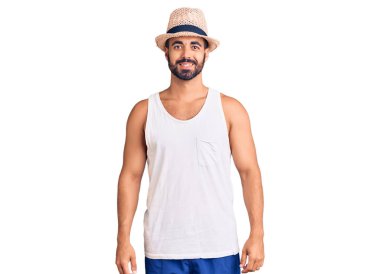 Yüzünde mutlu ve havalı bir gülümseme olan sıradan bir yaz şapkası takan İspanyol genç bir adam. şanslı kişi. 