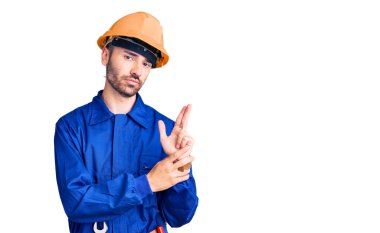 İspanyol üniformalı genç bir adam sembolik bir silah taşıyor. El hareketleriyle cinayet silahlarıyla oynuyor. Kızgın bir yüz. 