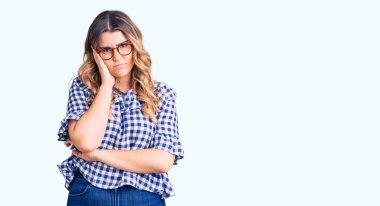 Gündelik giysiler giyen genç beyaz kadın kollarını kavuşturarak depresyondan sıkılmış ve yorgun görünüyor.. 