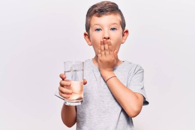 Sarışın, tatlı bir çocuk bir bardak su içiyor. Ağzını eliyle kapatıyor. Şok geçiriyor ve hata yapmaktan korkuyor. şaşırmış ifade 
